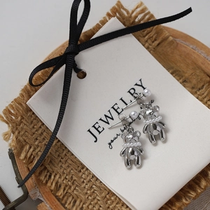 Macro view of silver bear stud earrings with pearl details on a jewelry display card