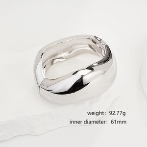 Polished silver minimalist irregular open bangle shown on a white stone base
