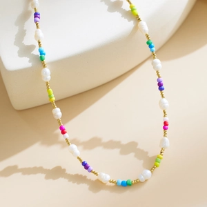 Detail of colorful beads, white pearls, and gold metal accents on a bohemian necklace