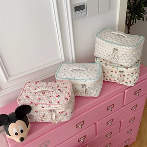 Quilted makeup bags in floral and cherry patterns on a pink drawer display