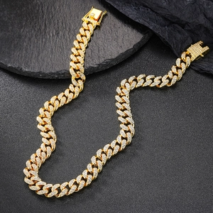 Close-up of 12mm gold plated Cuban link chain with pave set clear rhinestones on dark stone
