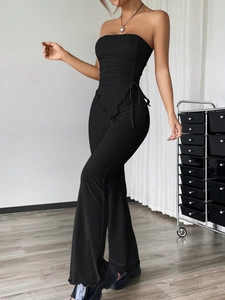 Detail of black tube top with side drawstring ruching and flare trousers on model