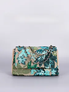 Detailed view of floral peacock blue sequins and green leaf embroidery on the woven shoulder bag