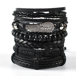 Close-up of multilayer black leather bracelet set with a detailed silver wing charm