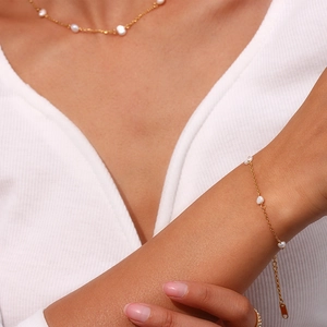 Close-up of elegant gold chain necklace and bracelet set with delicate white pearls