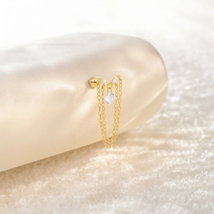 Macro detail of 925 silver gold tassel earring with zircon drop on a model ear