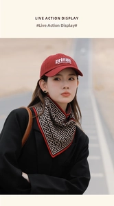 Detail of a geometric maze pattern scarf with red border and burgundy prince baseball cap