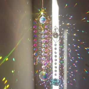 Crystal suncatcher with geometric gold frame and prism pendants casting rainbow light