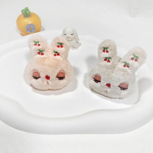 Close-up of plush rabbit hair accessories with cherry embroidery on a white tray