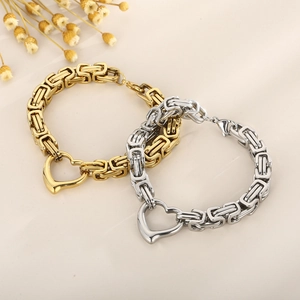 Detailed shot of gold and silver square link bracelets with a heart pendant on beige backdrop