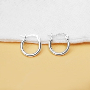 Close-up of polished S925 sterling silver hoop earrings on textured fabric