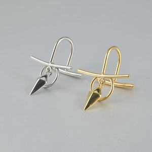 Detailed view of gold and silver U-shaped lip rings with minimalist conical pendants