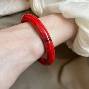 Detail of red resin cuff bracelet with marble texture worn on woman wrist