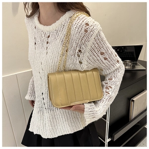 Model wearing a gold quilted chain bag over the shoulder with a stylish white knit top