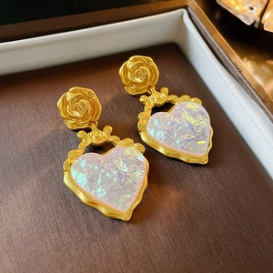 Vue macro de boucles d'oreilles fleurs dorées avec cœurs irisés et nœuds élégants