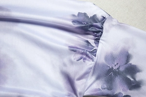 Détail macro du tissu tie-dye floral lavande et coutures précises au niveau de l'épaule