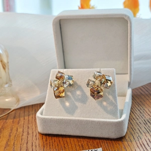 Elegant geometric cube crystal stud earrings in amber and champagne tones in a jewelry box