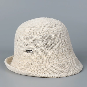 Close-up of beige knit bucket hat featuring textured weave and silver oval logo detail