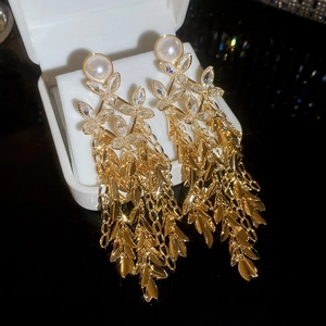 Macro shot of gold plated flower fringe earrings with pearls in a white jewelry box