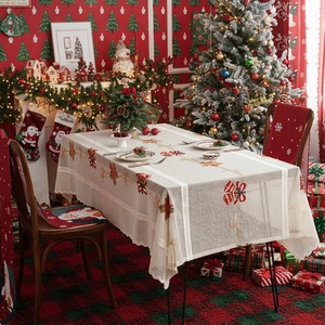 Christmas tablecloth with red bow embroidery and festive chair covers in holiday setting