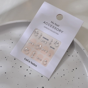 Detail of silver nail jewelry set with pearls in a ceramic tray, bow and ring designs