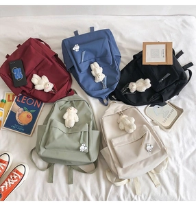 Flat lay of five colorful canvas school backpacks with cute plush bear charms and stickers