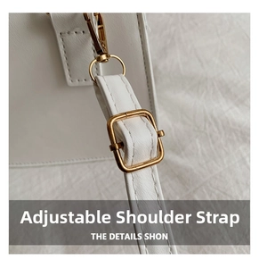 Detail of adjustable shoulder strap on white faux leather bag with gold metal buckle