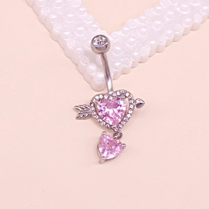 Detailed view of silver heart navel ring with pink gemstone and arrow on peach background