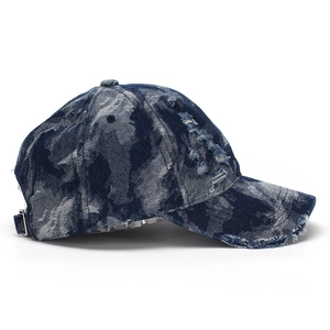 Detail of distressed navy denim baseball cap with frayed holes and metal buckle