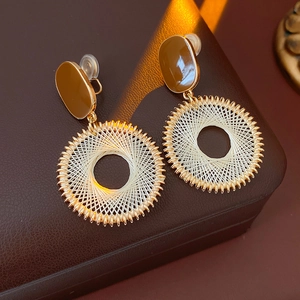 Detail of gold grid mesh circular earrings on a premium leather jewelry box display