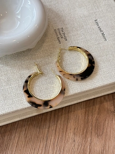 Detailed view of amber tortoiseshell resin C-shaped hoop earrings on a vintage book