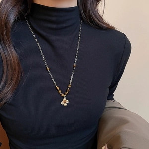 Detail of vintage flower pendant necklace with tiger eye beads on black turtleneck