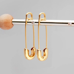 Dettaglio degli orecchini a spilla da balia dorati con design minimalista moderno