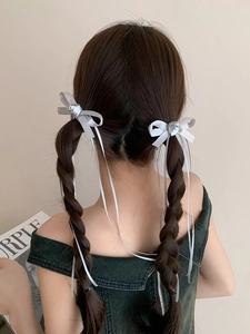 Détail de barrettes à nœuds en soie argentée avec roses et longs rubans fins