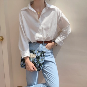 Close-up of a white cotton shirt with loose silhouette and button-down collar detail