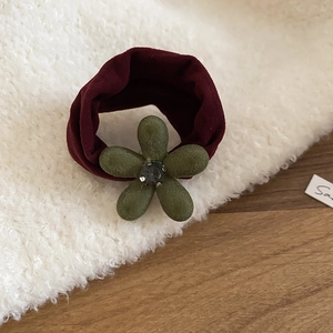 Détail de l'élastique à cheveux fleur floquée avec strass central et texture veloutée