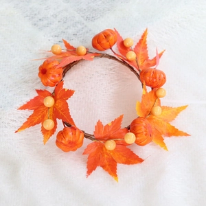Detail of autumn candle ring with maple leaves, mini pumpkins and berries for Halloween décor