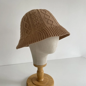 Close-up of camel knit bucket hat featuring thick cable weave and textured fabric