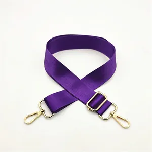 Detail of adjustable purple nylon shoulder strap with gold metal hooks and textured weave
