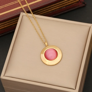 Detail of pink cat-eye stone pendant on golden stainless steel necklace in jewelry box