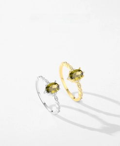 Macro detail of silver and gold rings with oval olive green gemstones and wave patterns