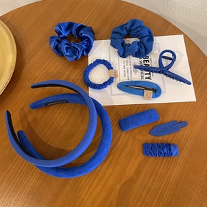 Flat lay of blue floral and velvet hair accessories set on a wooden table surface