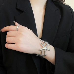 Detailed view of silver metal starfish cuff bracelet with textured surface on model