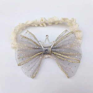 Detail of baby headband with grey tulle bow, lace strap, and sparkling gold crown charm
