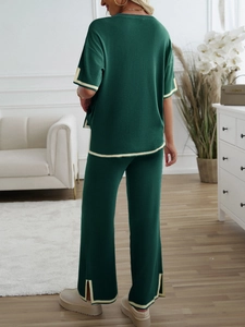 Rear view of green knit set with contrast piping and side slit wide leg pants