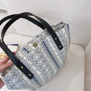 Detail of floral embroidery on canvas tote with leather handle and metal rivets