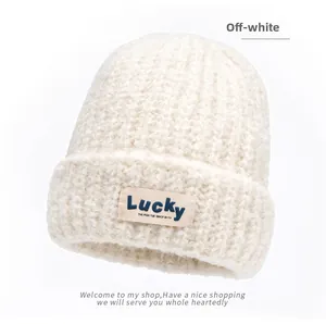 Close-up of off-white thick knit beanie with Lucky tag branding and premium ribbed texture