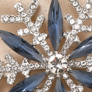 Macro detail of snowflake brooch with deep blue marquise gems and silver setting
