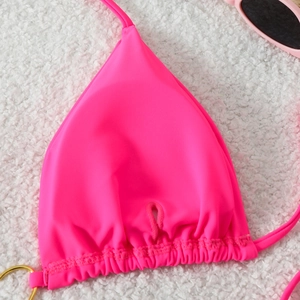 Detail of neon pink bikini top with triangle cups, ruched hem and gold ring ornament