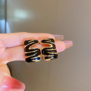 Close-up of vintage style black and gold wavy striped earrings with a polished finish